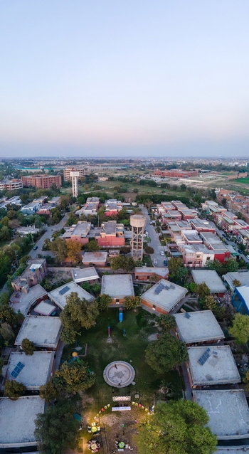 Aerial view of a residential complex with flat rooftops solar panels and a water tower surrounded by green spaces in Lahore Punjab Pakistan. Aerial view of a residential complex with flat rooftops solar panels and a water tower surrounded by green spaces in Lahore Punjab Pakistan.