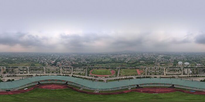 Aerial view of Pakansari Stadium with its distinctive curved roof and surrounding green fields under a cloudy sky in Kecamatan Cibinong Jawa Barat Indonesia. Aerial view of Pakansari Stadium with its distinctive curved roof and surrounding green fields under a cloudy sky in Kecamatan Cibinong Jawa Barat Indonesia.