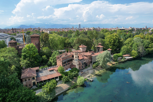 Aerial view of Borgo Medievale with its historic castle towers and lush green trees along the Po River in Torino Piemonte Italy.