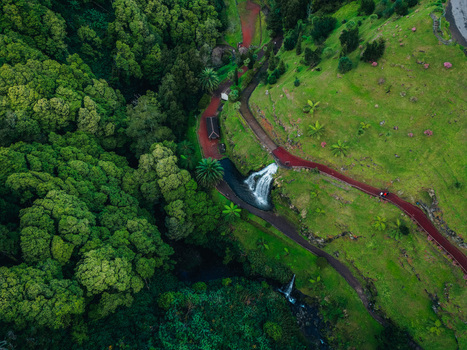 Aerial view of a cascade of water flowing through verdant forests and manicured green spaces divided by red earth paths Achada Açores Portugal. Aerial view of a cascade of water flowing through verdant forests and manicured green spaces divided by red earth paths Achada Açores Portugal.