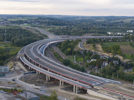 Aerial view of a large highway interchange under construction with concrete pillars and curved road sections surrounded by green fields and rural landscape in Krakow Lesser Poland Voivode Poland.
