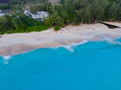 Aerial view of turquoise waters meet the white sandy beach fringed by lush greenery and a modern villa Quatre Bornes Mahe Island Seychelles. Aerial view of turquoise waters meet the white sandy beach fringed by lush greenery and a modern villa Quatre Bornes Mahe Island Seychelles.