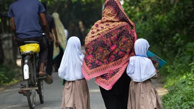 View of a woman walking with schoolgirls on a path Bangladesh.