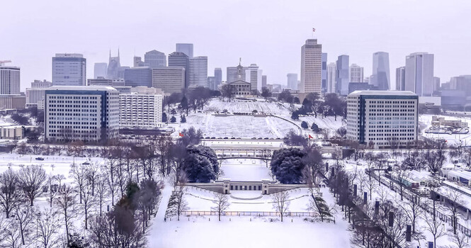Aerial view of the Tennessee State Capitol building surrounded by a snow covered park with the Nashville skyline in the background. Nashville Tennessee United States. Aerial view of the Tennessee State Capitol building surrounded by a snow covered park with the Nashville skyline in the background. Nashville Tennessee United States.