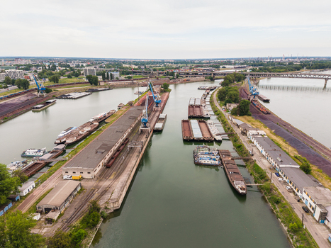 Aerial view of the industrial port area with cargo barges blue cranes and railway tracks along the Danube river under an overcast sky Bratislava Bratislava Region Slovakia. Aerial view of the industrial port area with cargo barges blue cranes and railway tracks along the Danube river under an overcast sky Bratislava Bratislava Region Slovakia.
