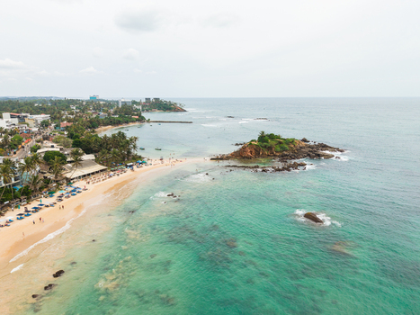 Aerial view of Parrot Rock and the sandy coastline of Mirissa Beach with turquoise ocean waves and palm trees Mirissa Southern Province Sri Lanka. Aerial view of Parrot Rock and the sandy coastline of Mirissa Beach with turquoise ocean waves and palm trees Mirissa Southern Province Sri Lanka.