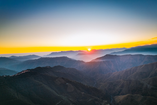 Aerial view of the sun rising over the layered mountain ridges and misty valleys in Chakrata Uttarakhand India. Aerial view of the sun rising over the layered mountain ridges and misty valleys in Chakrata Uttarakhand India.