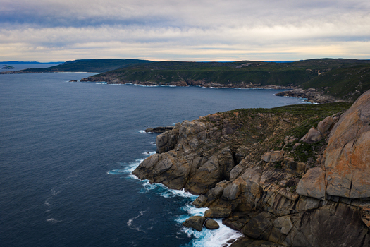 Aerial view of Jimmy Newells Harbour featuring rugged granite cliffs deep blue ocean waters and coastal vegetation in Albany WA Australia. Aerial view of Jimmy Newells Harbour featuring rugged granite cliffs deep blue ocean waters and coastal vegetation in Albany WA Australia.