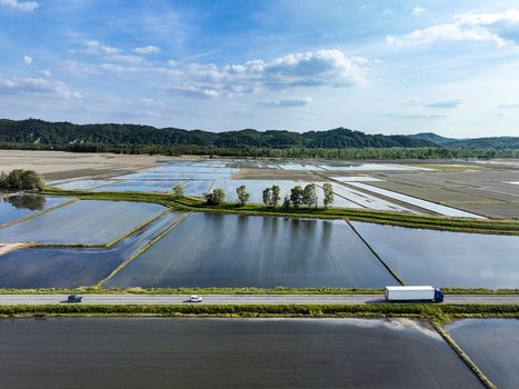 Aerial view of flooded rice fields with a road crossing the landscape and hills in the background near Trino Piedmont Italy.