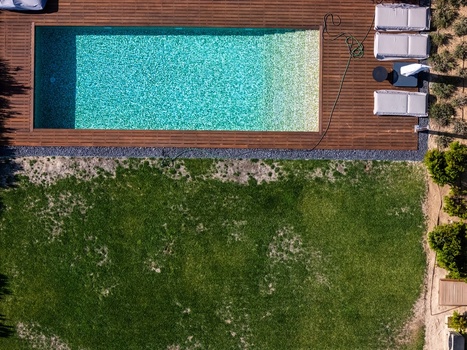 Aerial view of a rectangular swimming pool with turquoise water wooden decking lounge chairs and a green lawn in Cascais Lisboa Portugal. Aerial view of a rectangular swimming pool with turquoise water wooden decking lounge chairs and a green lawn in Cascais Lisboa Portugal.