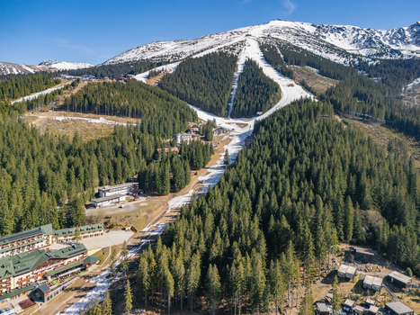 Aerial view of the Jasna ski resort in Demanovska Dolina with snow covered slopes dense pine forests and mountain hotels under a clear blue sky in Demanovska Dolina Zilina Region Slovakia.