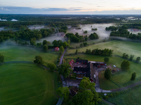 Aerial view of traditional red farmhouses surrounded by morning mist and green fields in the countryside Gundrastorp Skane County Sweden. Aerial view of traditional red farmhouses surrounded by morning mist and green fields in the countryside Gundrastorp Skane County Sweden.