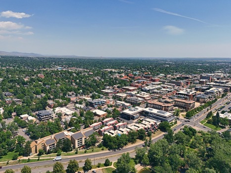 Aerial view of the city of Boulder with its dense urban layout lush green trees and surrounding landscape under a clear blue sky in Boulder Colorado United States. Aerial view of the city of Boulder with its dense urban layout lush green trees and surrounding landscape under a clear blue sky in Boulder Colorado United States.