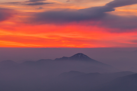 Aerial view of Velky Choc mountain peak rising above a sea of mist during a vibrant sunset with glowing orange and red clouds in the sky in Vysny Kubin Zilina Region Slovakia. Aerial view of Velky Choc mountain peak rising above a sea of mist during a vibrant sunset with glowing orange and red clouds in the sky in Vysny Kubin Zilina Region Slovakia.