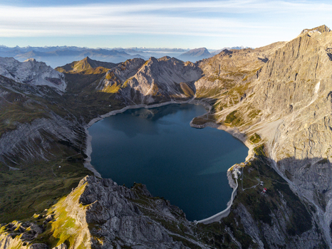 Aerial view of Lunersee surrounded by rugged alpine peaks rocky mountain slopes and clear blue water in the Ratikon mountain range Vandans Vorarlberg Austria. Aerial view of Lunersee surrounded by rugged alpine peaks rocky mountain slopes and clear blue water in the Ratikon mountain range Vandans Vorarlberg Austria.