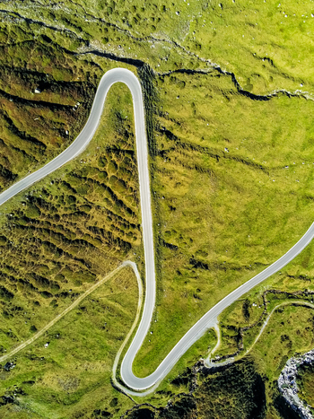 Aerial view of Silvretta Hochalpenstrasse winding through lush green alpine meadows with sharp hairpin turns Partenen Vorarlberg Austria. Aerial view of Silvretta Hochalpenstrasse winding through lush green alpine meadows with sharp hairpin turns Partenen Vorarlberg Austria.