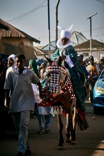 Zaria City Nigeria 21 March 2026 View of a regal figure in striking green and white attire on an ornately decorated horse leading a vibrant procession through sun drenched streets. Zaria City Nigeria 21 March 2026 View of a regal figure in striking green and white attire on an ornately decorated horse leading a vibrant procession through sun drenched streets.