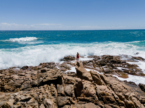 Aerial view of a woman in a red dress standing on the rocky coastline at Injidup Natural Spa with crashing waves and turquoise water in Yallingup Western Australia Australia. Aerial view of a woman in a red dress standing on the rocky coastline at Injidup Natural Spa with crashing waves and turquoise water in Yallingup Western Australia Australia.