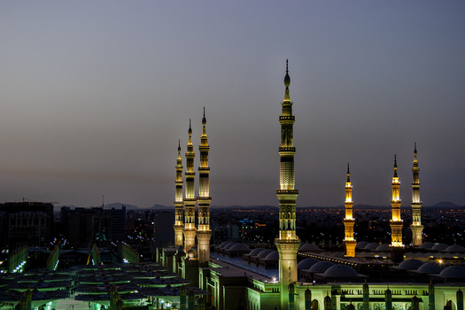 View of the illuminated minarets of Al Masjid e Nabawi at twilight in Madinah Al Madinah Province Saudi Arabia.