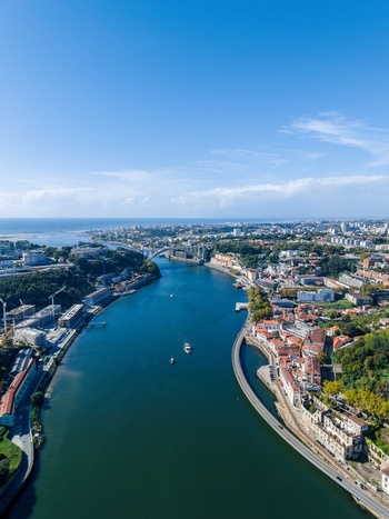 Aerial view of the Viaduto do Cais das Pedras spanning the Douro River surrounded by historic buildings lush greenery and urban infrastructure in Porto Porto Portugal.