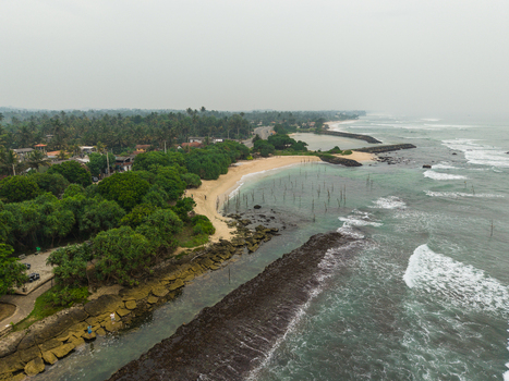 Aerial view of traditional stilt fishing poles in the shallow water along the sandy coastline and lush tropical greenery Koggala Southern Province Sri Lanka. Aerial view of traditional stilt fishing poles in the shallow water along the sandy coastline and lush tropical greenery Koggala Southern Province Sri Lanka.