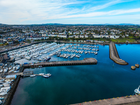 Aerial view of Bangor Harbour and Town with a marina filled with boats a stone breakwater and coastal town buildings under a blue sky in Bangor Northern Ireland United Kingdom.