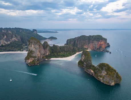 Aerial view of towering limestone cliffs meet the turquoise sea fringed by white sands and lush greenery Krabi Thailand. Aerial view of towering limestone cliffs meet the turquoise sea fringed by white sands and lush greenery Krabi Thailand.