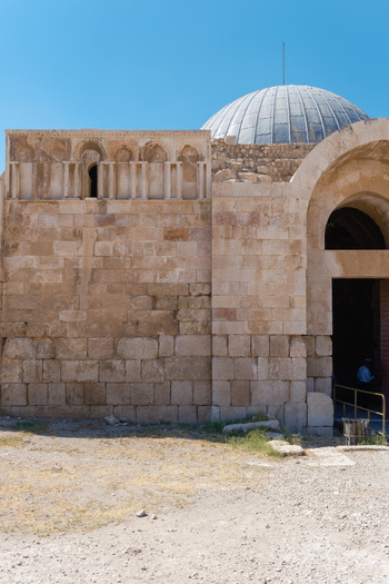 View of the historic Umayyad Palace with its stone masonry arched entrance and dome under a clear blue sky in Amman Amman Governorate Jordan.