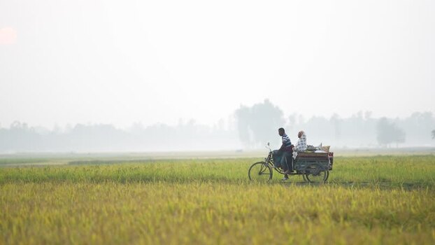 View of people on a cart through rural fields in Bogura Bangladesh.
