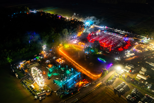 Herzogenaurach Germany 24 July 2025 Aerial view of Open Beatz Festival with illuminated stages a Ferris wheel and crowds of people under colorful lights at night.