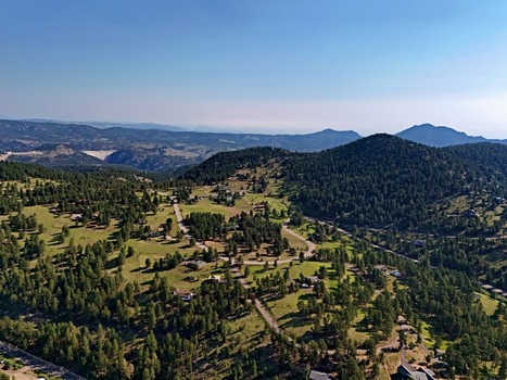 Aerial view of the residential area and winding roads surrounded by dense pine forests and mountains in Coal Creek Colorado United States. Aerial view of the residential area and winding roads surrounded by dense pine forests and mountains in Coal Creek Colorado United States.