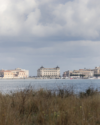 View of the historic Ortigia island waterfront with grand architecture and the Grand Hotel Des Etrangers across the water Syracuse Sicily Italy.
