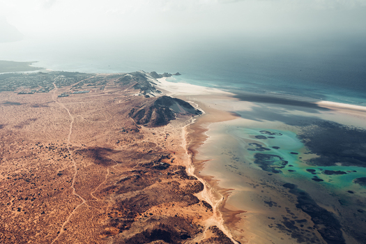 Aerial view of Detwah Lagoon featuring white sand beaches and turquoise waters along the rugged coastline in Qalansiyah wa Abd Al Kuri Socotra Yemen. Aerial view of Detwah Lagoon featuring white sand beaches and turquoise waters along the rugged coastline in Qalansiyah wa Abd Al Kuri Socotra Yemen.
