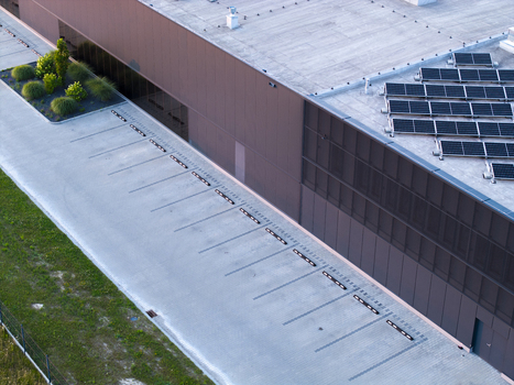 Aerial view of a modern industrial building with rooftop solar panels and an empty parking lot in Poland. Aerial view of a modern industrial building with rooftop solar panels and an empty parking lot in Poland.