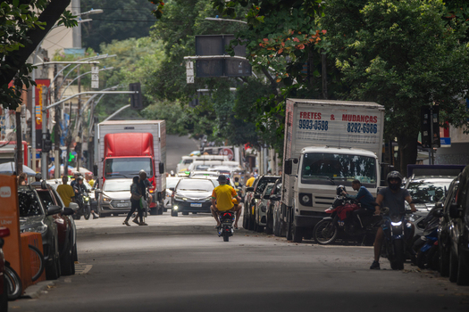 Rio de Janeiro Brazil 13 June 2026 View of a busy street in the Copacabana neighborhood with delivery trucks cars and people on motorcycles under lush green trees.