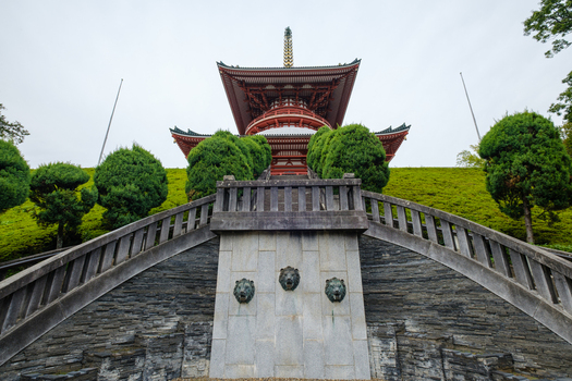 View of the imposing red pagoda framed by manicured green shrubbery and stone steps adorned with lion heads stands majestically Narita Chiba Japan. View of the imposing red pagoda framed by manicured green shrubbery and stone steps adorned with lion heads stands majestically Narita Chiba Japan.
