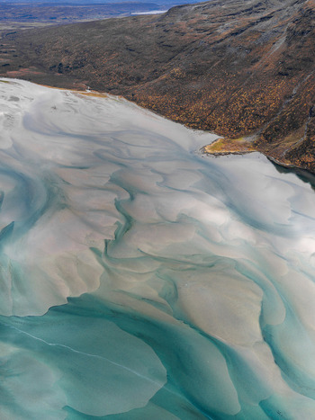 Aerial view of the tidal flats and turquoise water channels of Senja with rugged mountains and autumn colored slopes in the background in Senja Troms Norway.