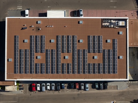 Aerial view of a large building roof covered with rows of solar panels with a parking lot containing several cars below in Elvas Portalegre Portugal. Aerial view of a large building roof covered with rows of solar panels with a parking lot containing several cars below in Elvas Portalegre Portugal.