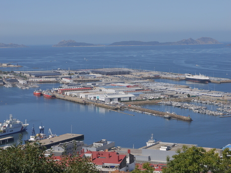 View of the busy Port of Vigo with industrial warehouses numerous parked cars docked yachts and cargo ships under a clear blue sky in Vigo Pontevedra Spain.