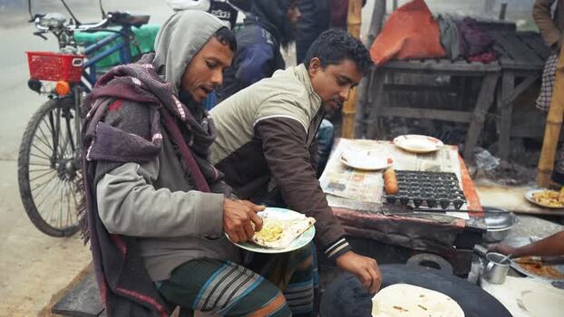 View of men eating street food at a stall in Bogura Bangladesh View of men eating street food at a stall in Bogura Bangladesh