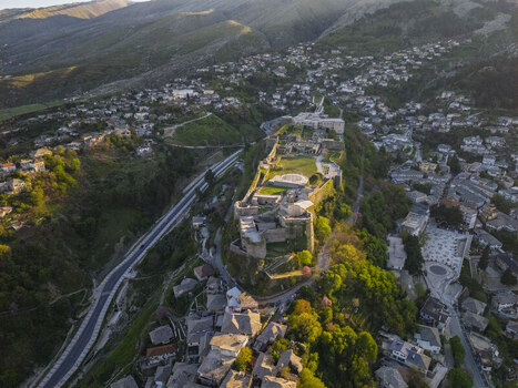 Aerial view of Gjirokaster Castle surrounded by historic stone houses and lush green hills in Gjirokaster Gjirokaster County Albania. Aerial view of Gjirokaster Castle surrounded by historic stone houses and lush green hills in Gjirokaster Gjirokaster County Albania.
