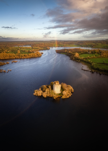 Aerial view of Cloughoughter Castle on a small island surrounded by calm lake waters and autumn foliage under a rainbow County Cavan Ireland. Aerial view of Cloughoughter Castle on a small island surrounded by calm lake waters and autumn foliage under a rainbow County Cavan Ireland.
