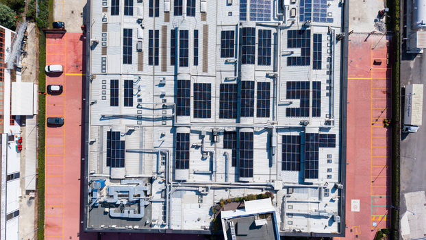 Aerial view of a food additive manufacturing plant featuring extensive solar panel arrays on the rooftop ventilation systems and a surrounding parking area in Milan Lombardy Italy. Aerial view of a food additive manufacturing plant featuring extensive solar panel arrays on the rooftop ventilation systems and a surrounding parking area in Milan Lombardy Italy.
