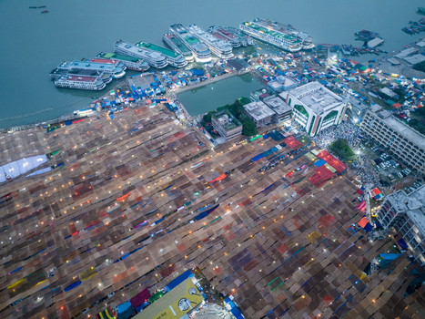 Aerial view of vibrant patterns of stalls contrast with the sleek lines of boats docked along the shore Charmonai Barisal Division Bangladesh. Aerial view of vibrant patterns of stalls contrast with the sleek lines of boats docked along the shore Charmonai Barisal Division Bangladesh.
