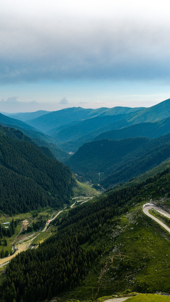 Aerial view of the winding Transfagarasan mountain pass surrounded by lush green forests and rugged peaks in Curtea de Arges Judetul Arges Romania. Aerial view of the winding Transfagarasan mountain pass surrounded by lush green forests and rugged peaks in Curtea de Arges Judetul Arges Romania.