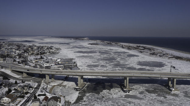 Aerial view of the Highlands Sea Bright Bridge spanning across the frozen Shrewsbury River with ice floes and snow covered coastal landscape in Highlands New Jersey United States. Aerial view of the Highlands Sea Bright Bridge spanning across the frozen Shrewsbury River with ice floes and snow covered coastal landscape in Highlands New Jersey United States.
