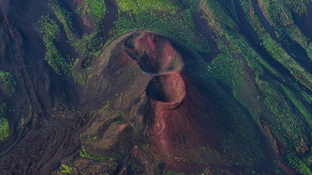 Aerial view of Mount Etna showing volcanic craters with reddish soil and green vegetation on the slopes in Castiglione di Sicilia Sicily Italy. Aerial view of Mount Etna showing volcanic craters with reddish soil and green vegetation on the slopes in Castiglione di Sicilia Sicily Italy.
