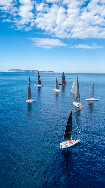 Aerial view of sailboats and yachts sailing on the calm blue Adriatic Sea with the island of Vis in the background under a cloudy sky in Komiza Split Dalmatia County Croatia. Aerial view of sailboats and yachts sailing on the calm blue Adriatic Sea with the island of Vis in the background under a cloudy sky in Komiza Split Dalmatia County Croatia.
