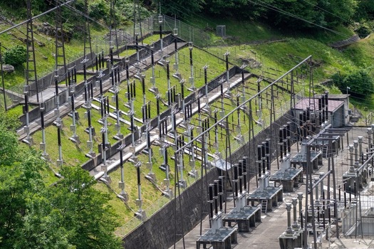 Aerial view of the electrical substation infrastructure at the Verzasca Dam with power lines and green hillsides in Gordola Ticino Switzerland. Aerial view of the electrical substation infrastructure at the Verzasca Dam with power lines and green hillsides in Gordola Ticino Switzerland.