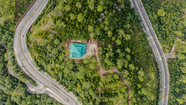 Aerial view of the Islamabad Murree Expressway winding through a lush forested mountain landscape with a building featuring a green roof in Lower Topa Punjab Pakistan. Aerial view of the Islamabad Murree Expressway winding through a lush forested mountain landscape with a building featuring a green roof in Lower Topa Punjab Pakistan.
